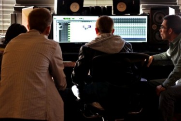 Three guys making electronic music at mixer and monitor